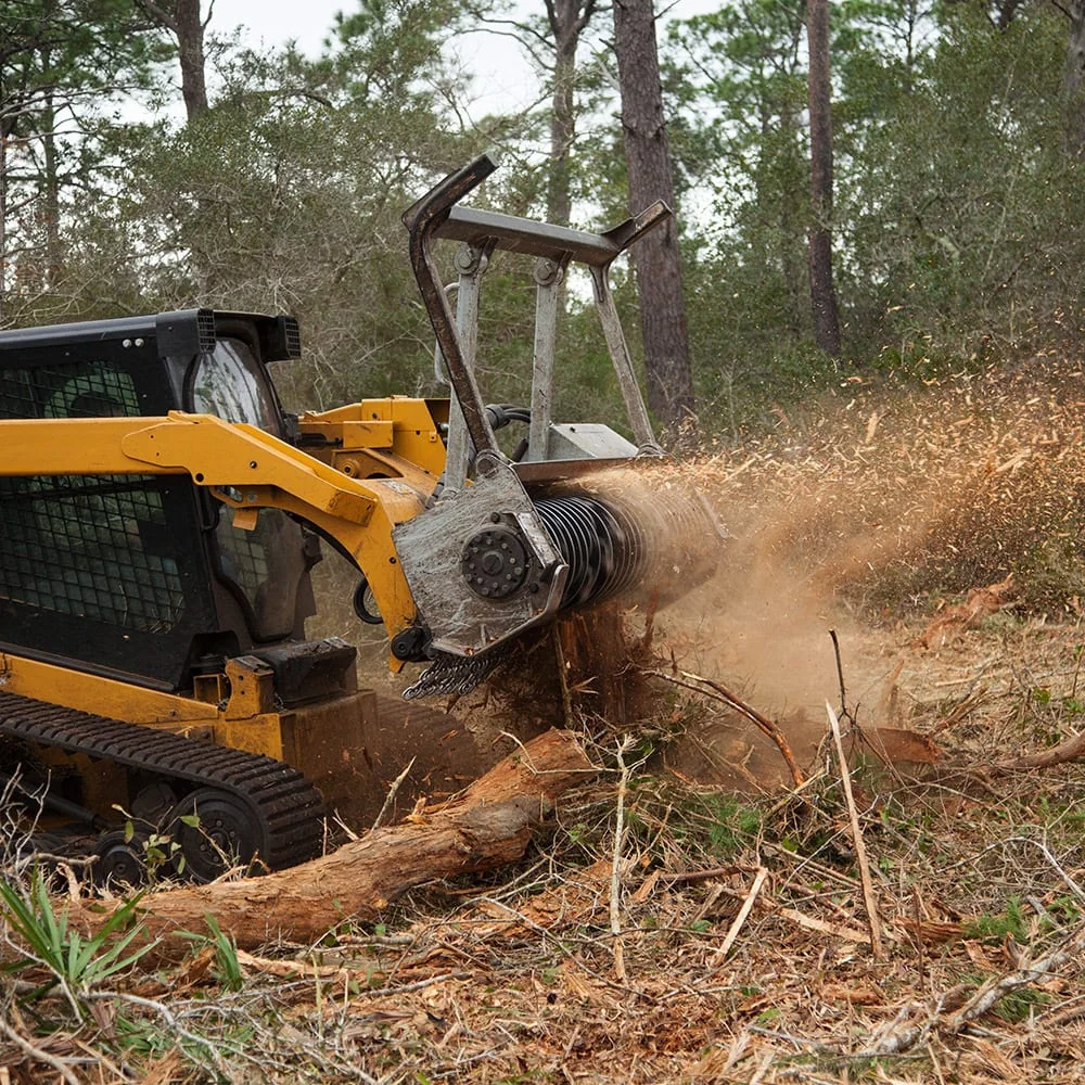 Tracked skid steer with forestry mulcher clearing brush